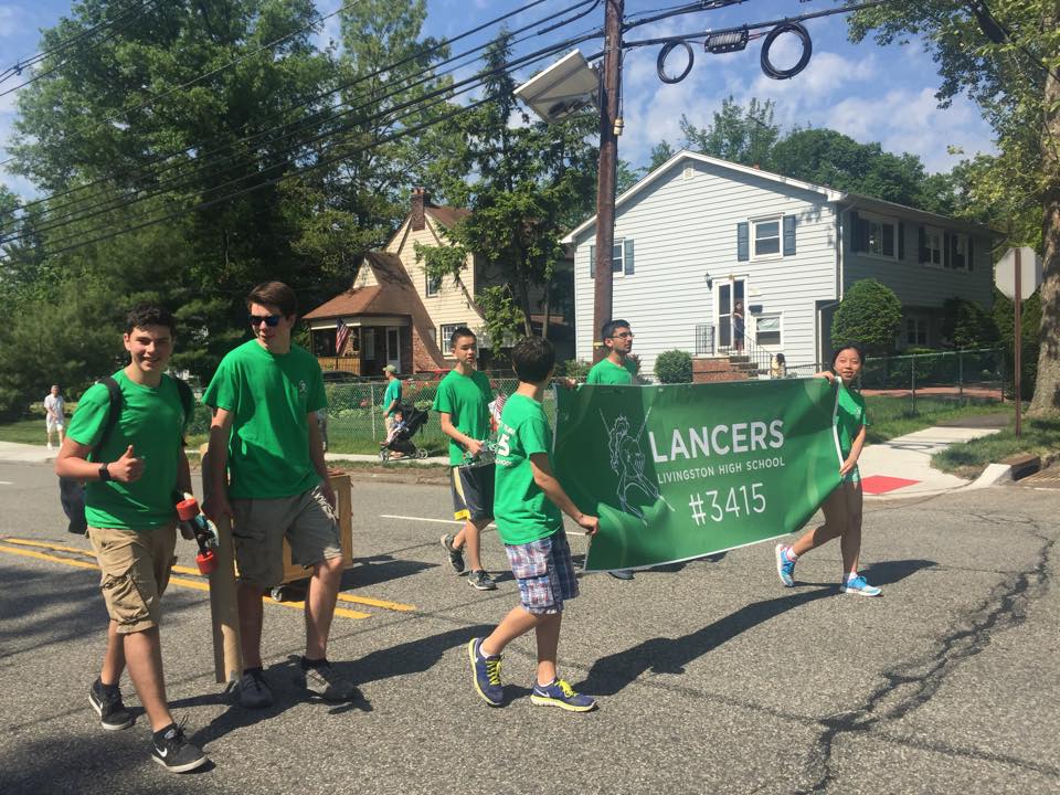 Lancer Robotics students carrying the Team 3415 banner at a Livingston community parade